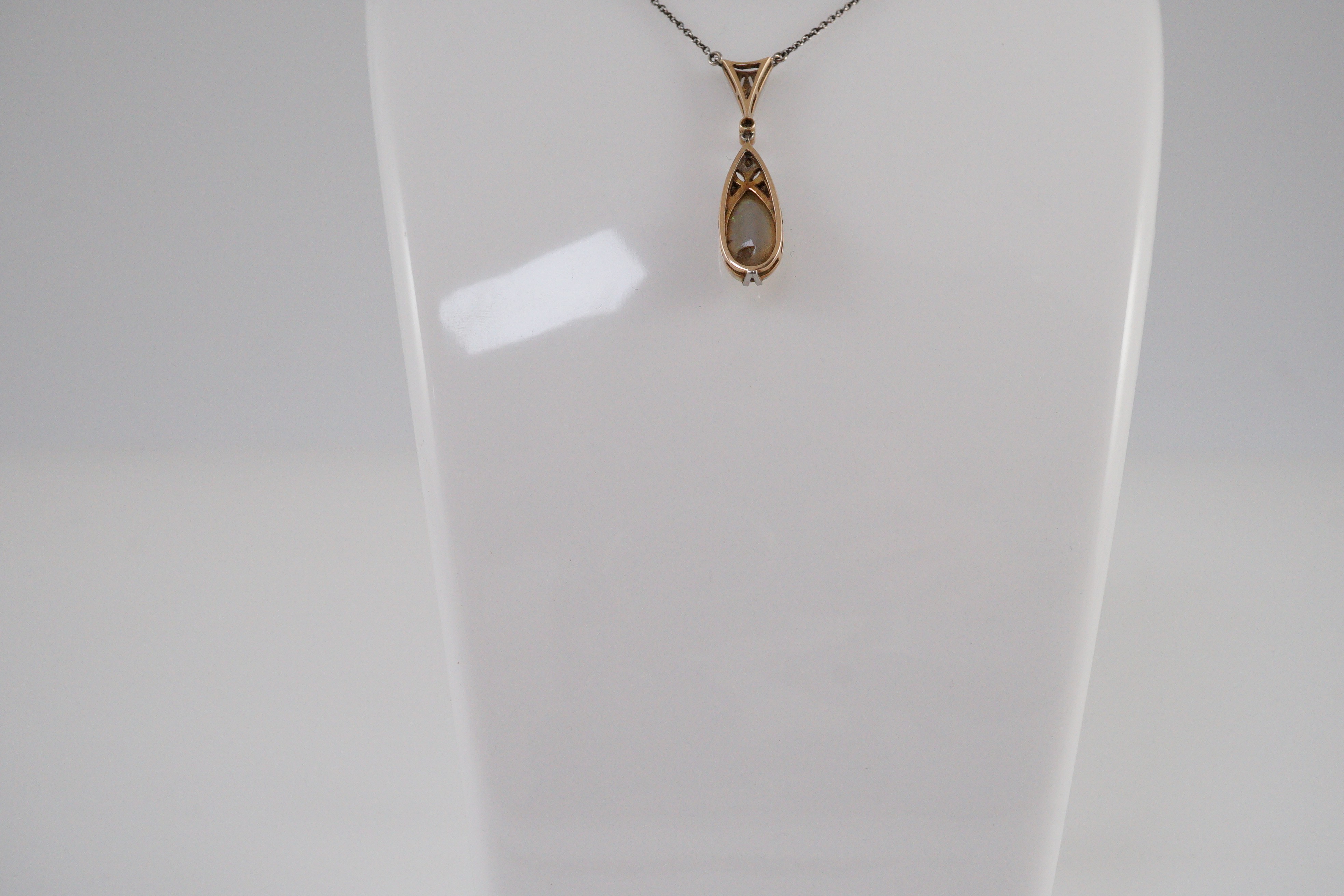 A 1920's gold and platinum, white opal and millegrain set diamond cluster pear shaped drop pendant necklace